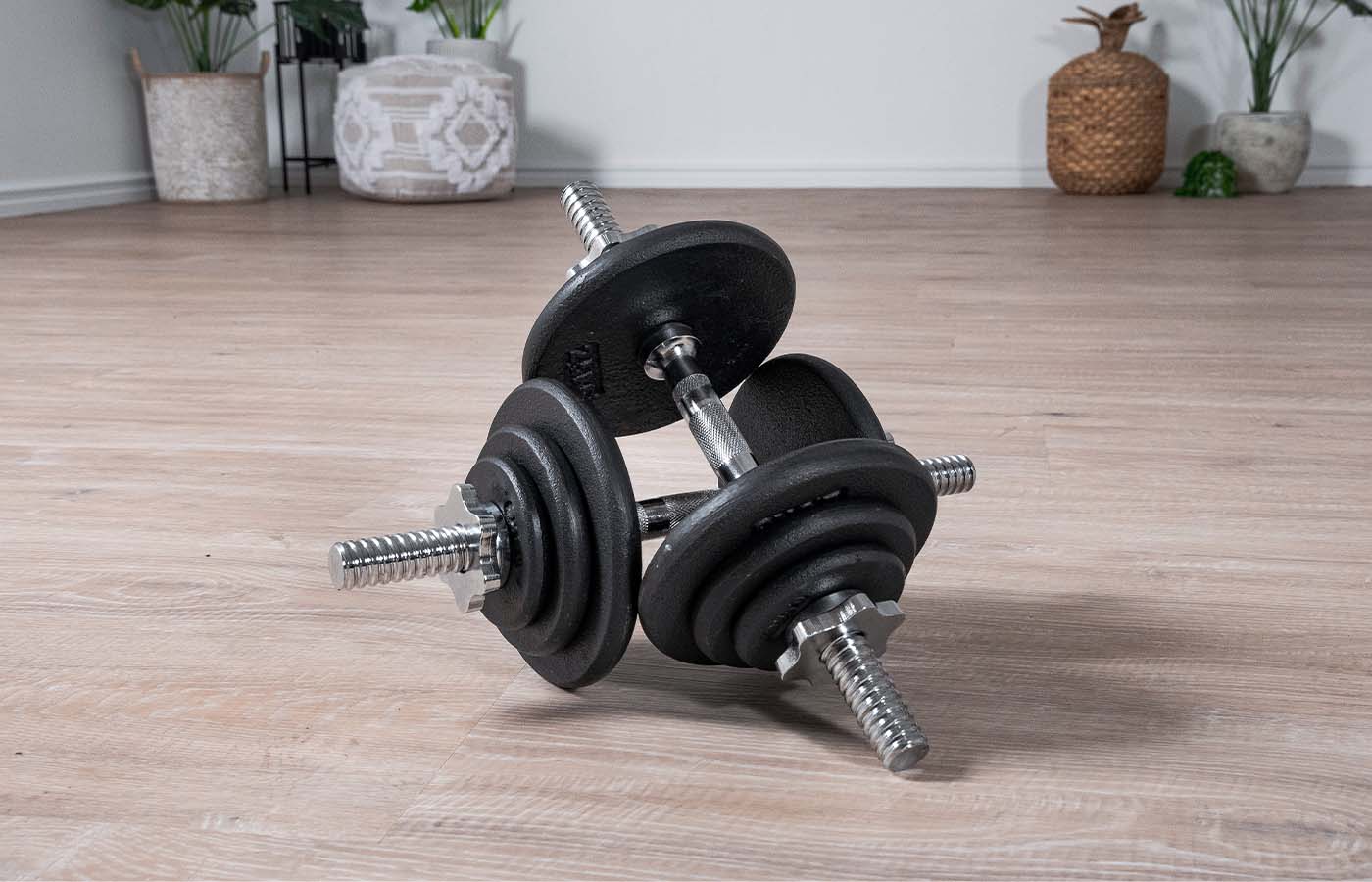 A pair of loaded dumbbells on the floor of a home workout space 